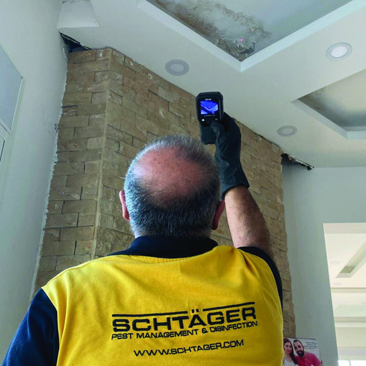 Schtager mold inspection: A technician inspecting a ceiling with a device, likely assessing for mold.