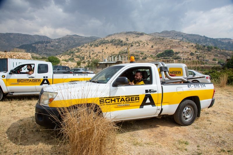 Schtager Pest Management pickup trucks deployed in a rural mountainous area, with technicians ready for pest control and disinfection services.